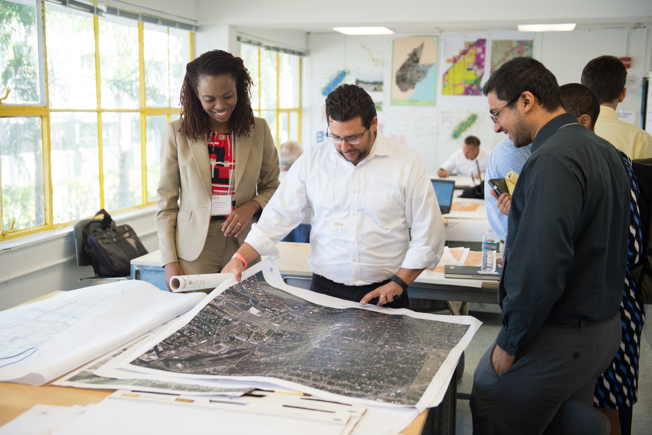 Photo of 3 professionals examining various maps and land studies of Miami-Dade County