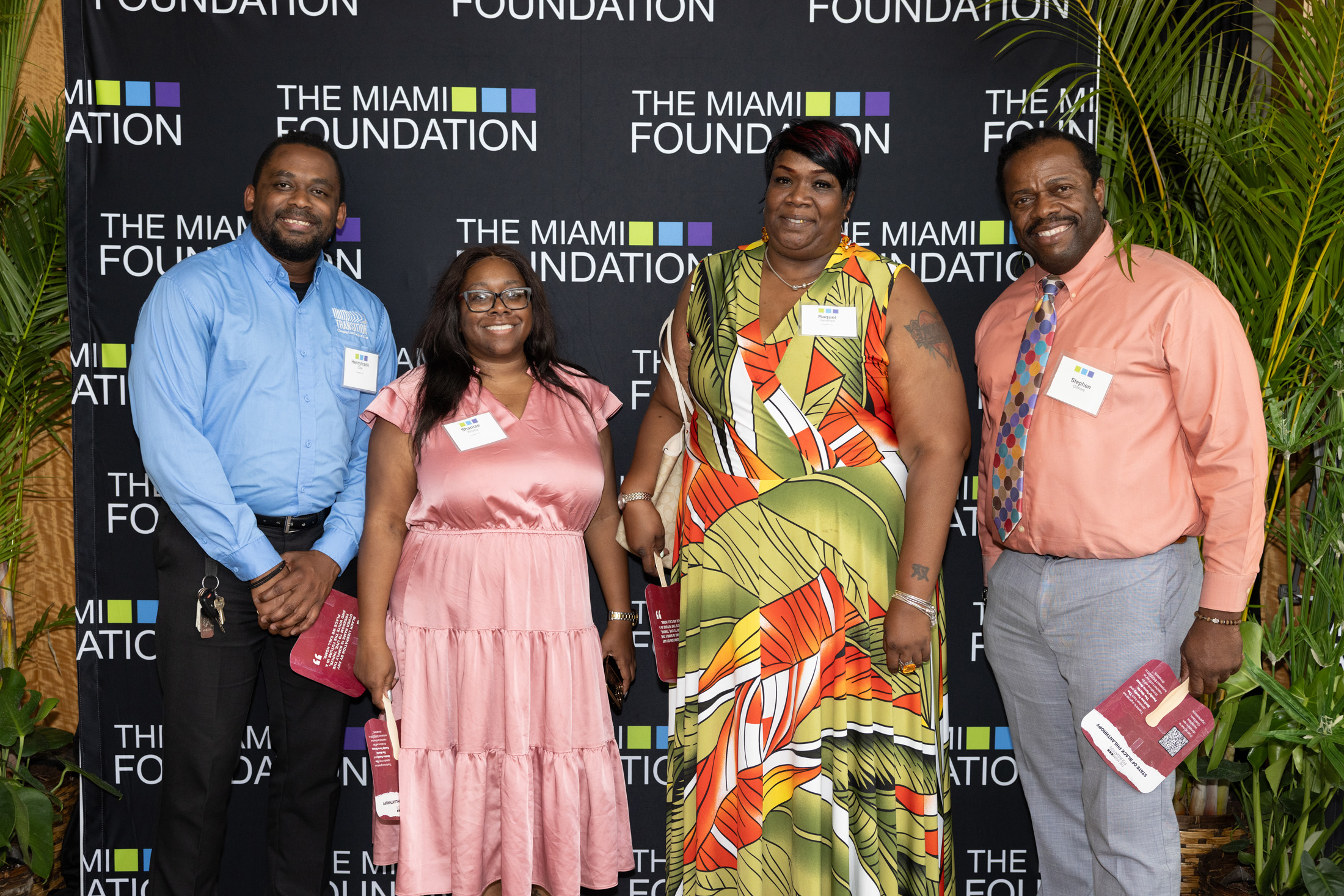 Four attendees smile in front of The Miami Foundation logo