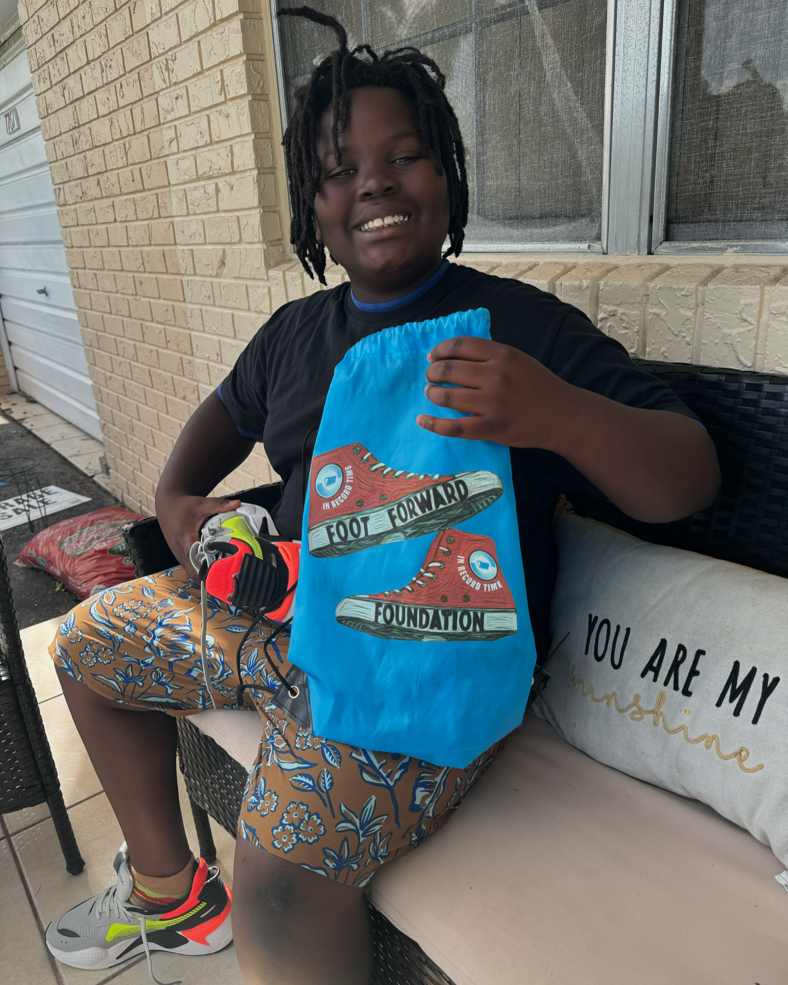 Child smiles on receiving a new pair of sneakers in a custom bag.