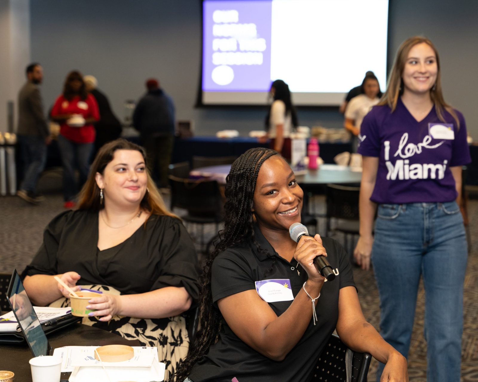 Nonprofit leader smiles with microphone while asking a question at a Give Miami Day capacity building session Nonprofit leader smiles with microphone while asking a question at a Give Miami Day capacity building session