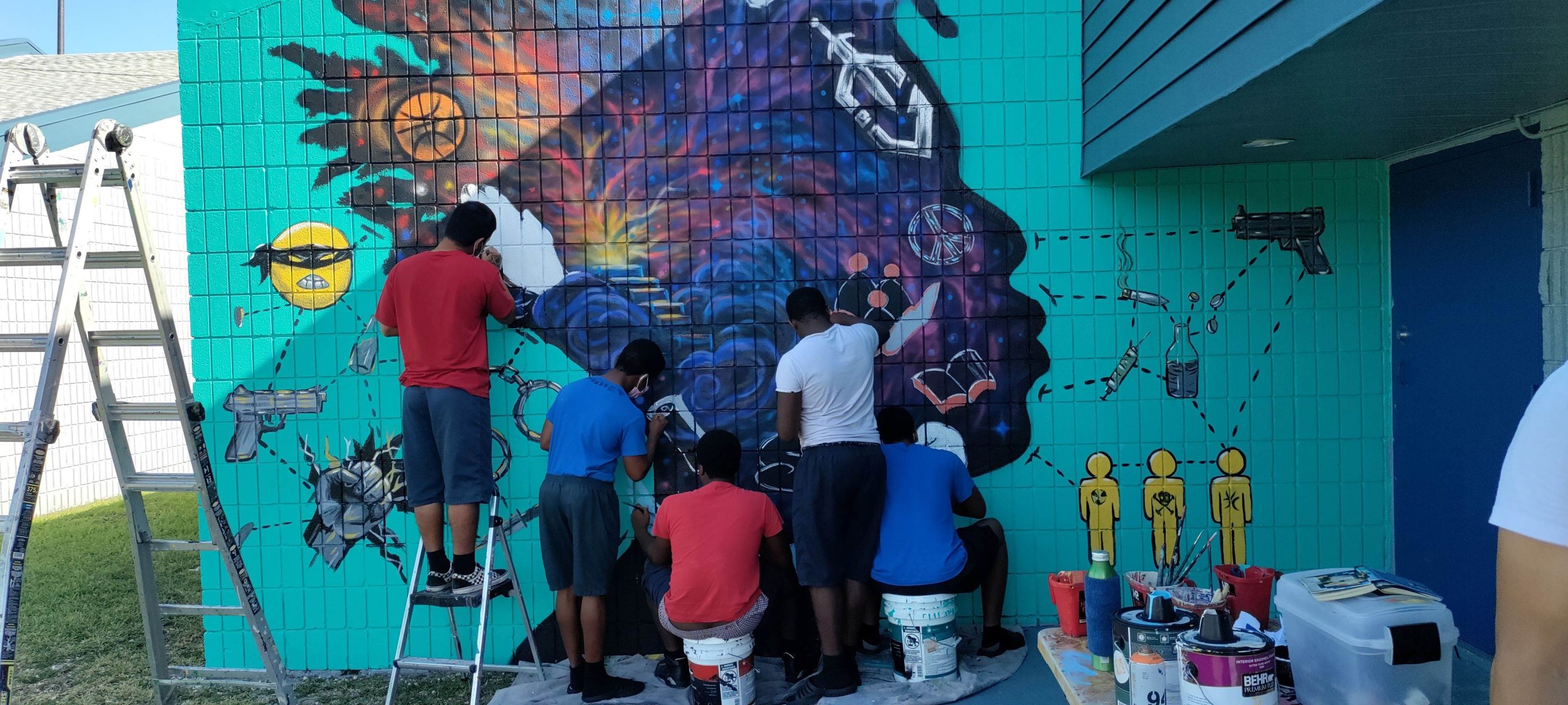 Group of volunteers paint an exterior mural.