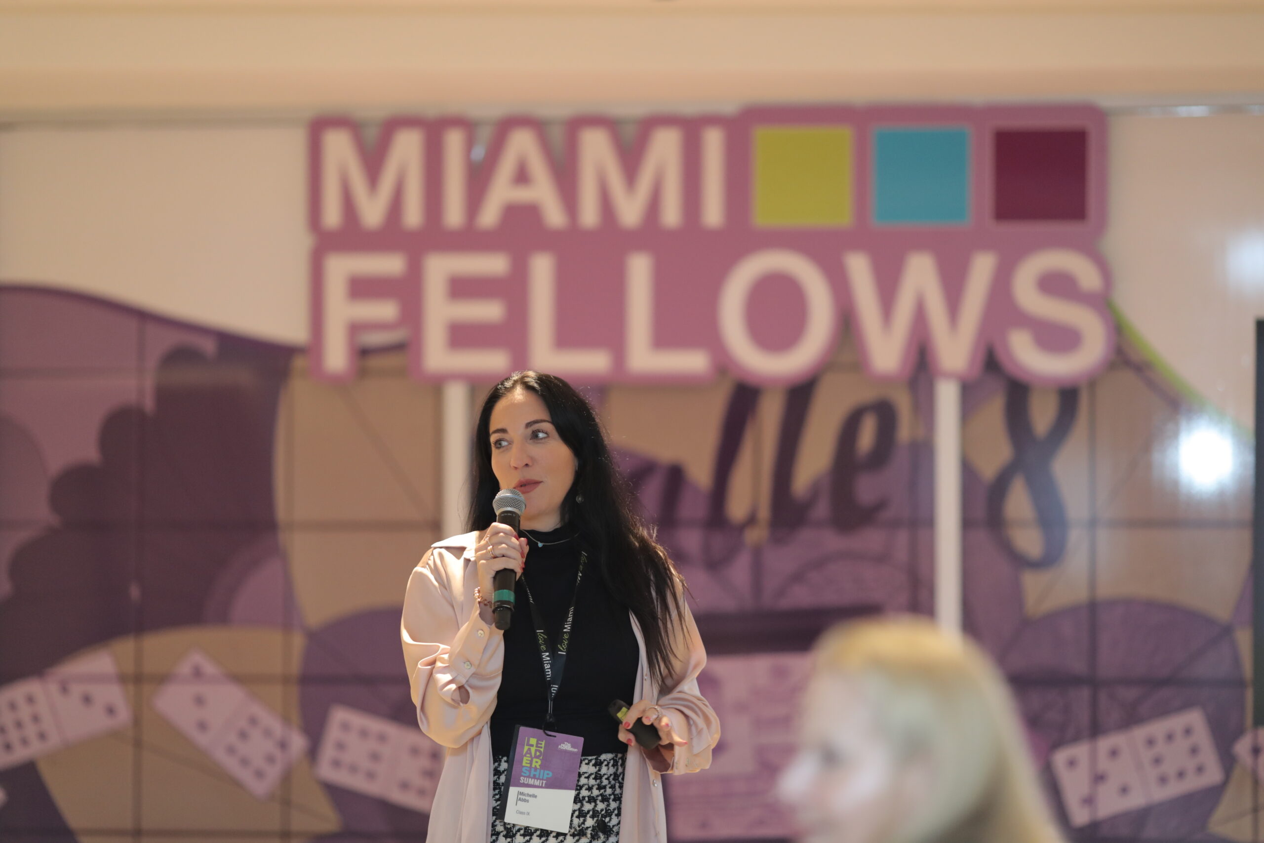 Woman speaks on stage at the Miami Fellows Summit