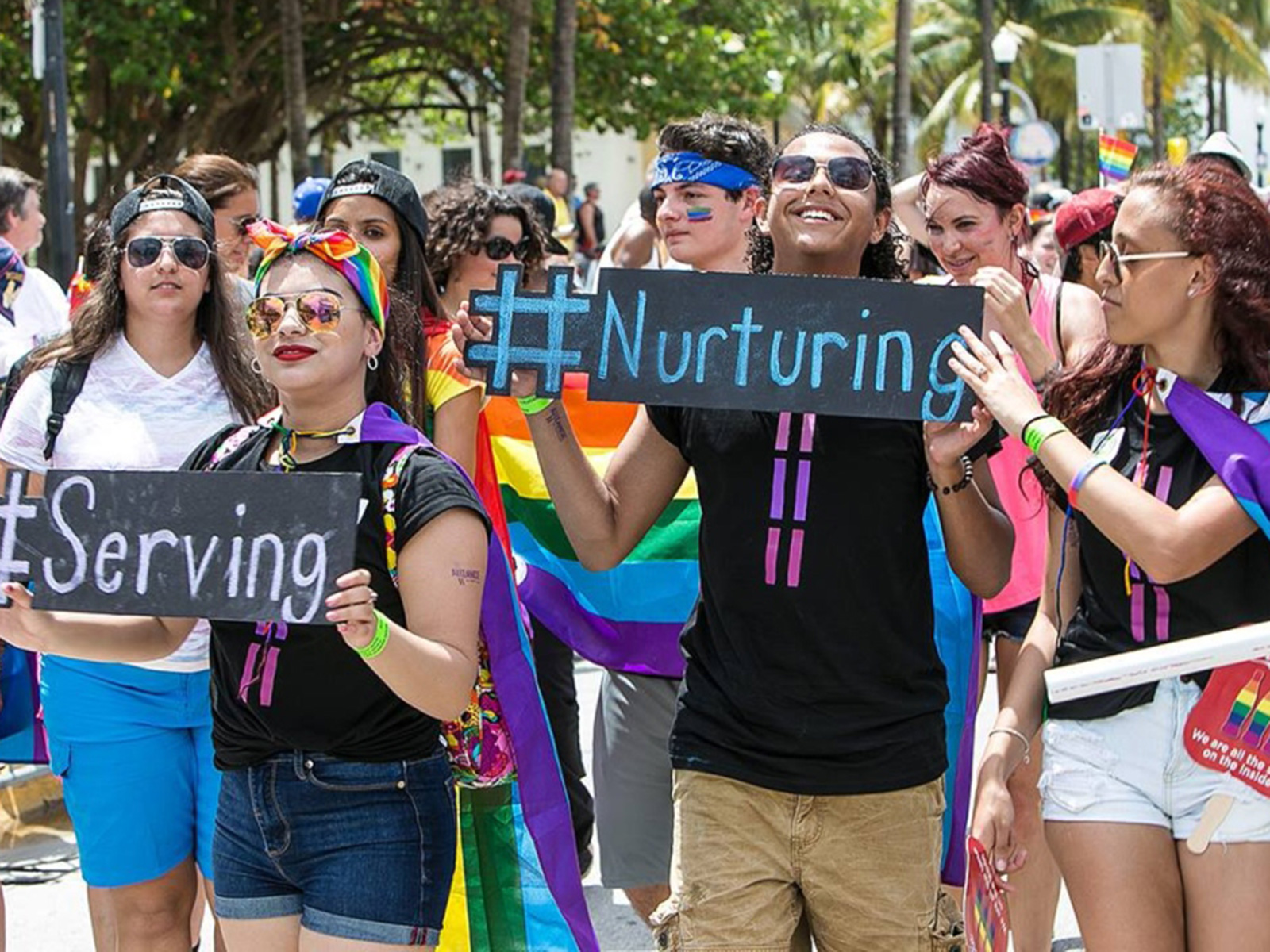 People in a group holding signs saying #serving and #nurturing
