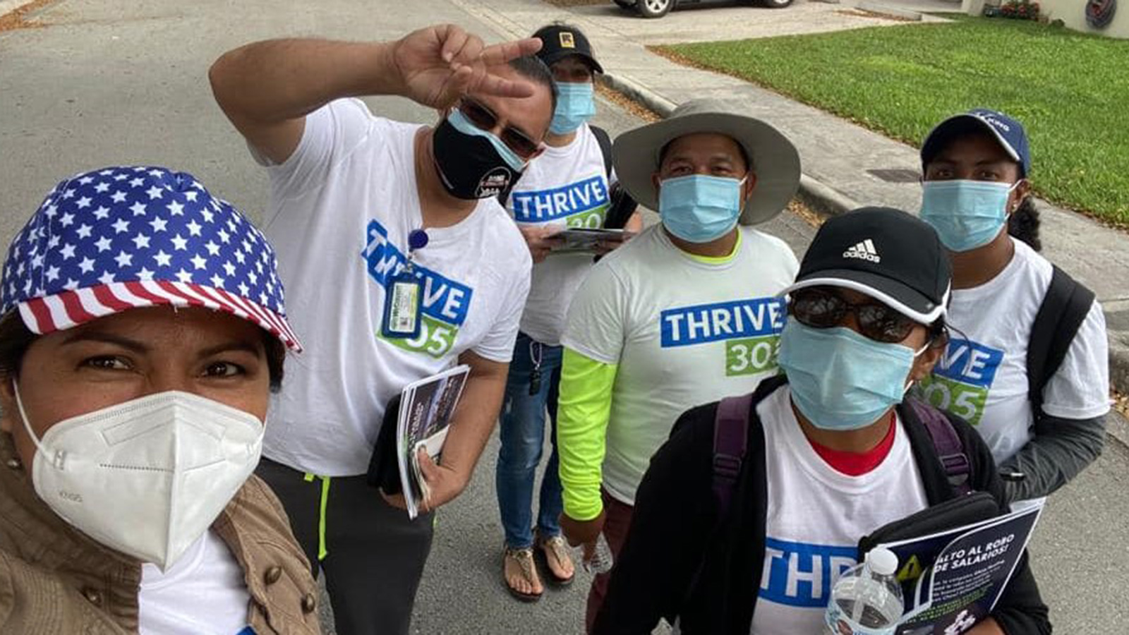 People wearing masks and Thrive 305 shirts taking a selfie