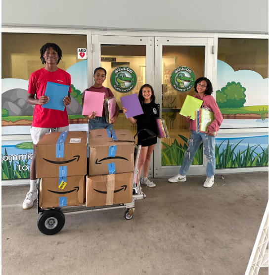 Children smiling in front of a cart full of deliveries.
