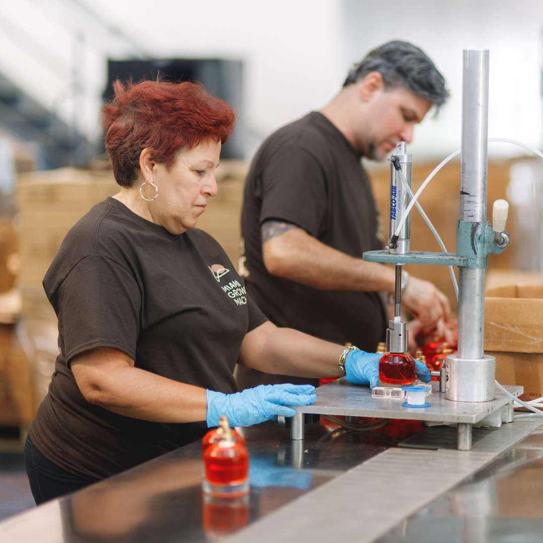 A man and woman work on bottling perfumes in a lab.